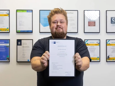René hält sein IHK Unternehmensberater Zertifikat hoch