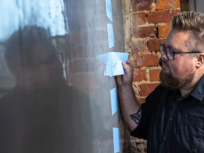 Klebezettel an einer Wand. René klebt Zettel an die.