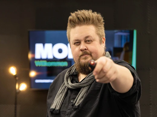 René hält einen Presenter in die Kamera