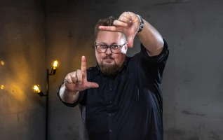 René deutet mit seinen Fingern ein Rechteck in der Luft ab.